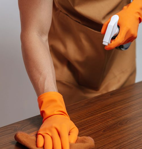 close-up-male-hand-using-cloth-wipes-wooden-cabinet-with-drawer-holding-spray-bottle-cleaning-furniture-home1